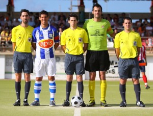 El colegiado con los asistentes y capitanes del partido