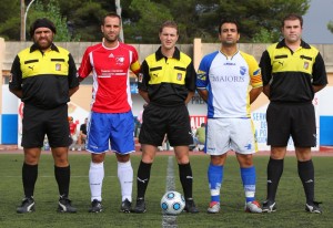 El trío arbitral con los capitanes del partido.