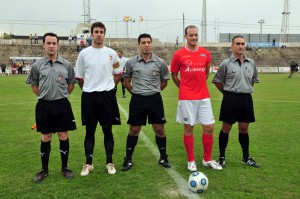 El trío arbitral con los capitanes del partido