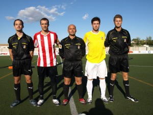 El trío arbitral con los capitanes del partido