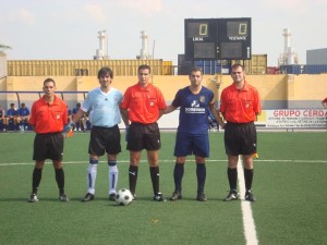 El trío arbitral con los capitanes del partido