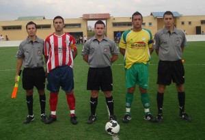 El trío arbitral con los capitanes del partido