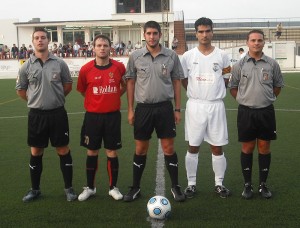 El trío arbitral con los capitanes del partido