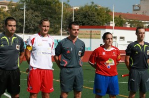 El trío arbitral con las capitanas del partido