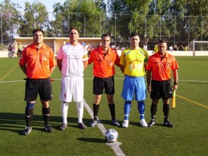 El trío arbitral con los capitanes del partido