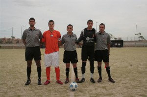 El trío arbitral con los capitanes del partido