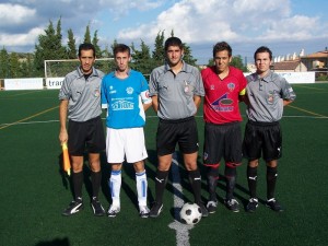 El trío arbitral con los capitanes del partido