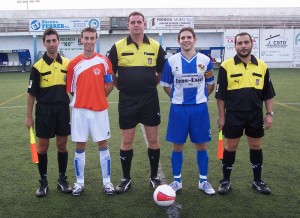 El trío arbitral con los capitanes del partido