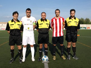 El trío arbitral con los capitanes del partido