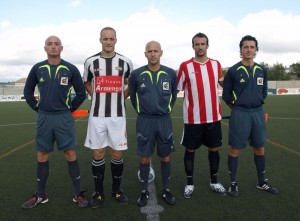 El trío arbitral con los capitanes del partido