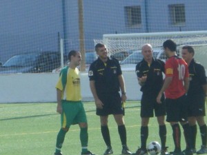 El trío arbitral con los capitanes del partido