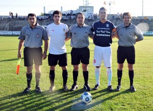 El trío arbitral con los capitanes del partido