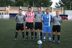 El trío arbitral con los capitanes del partido