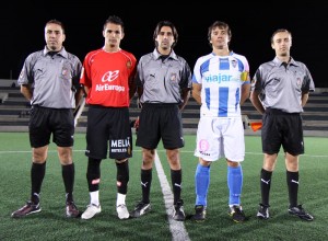 El trío arbitral con los capitanes del partido