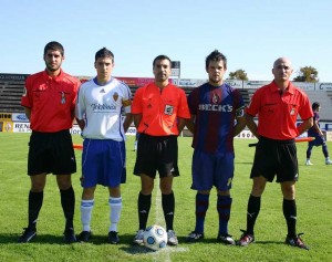 El trío arbitral con los capitanes del partido