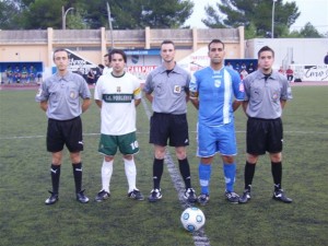 El trío arbitral con los capitanes del partido