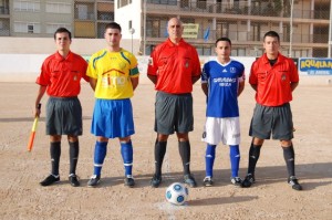 El trío arbitral con los capitanes del partido