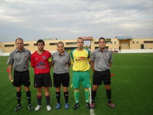 El trío arbitral con los capitanes del partido