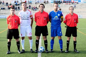 El trío arbitral con los capitanes del partido