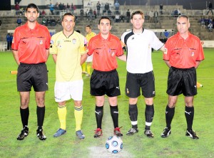 El trío arbitral con los capitanes del partido