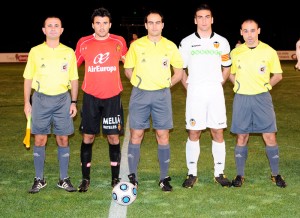 El trío arbitral con los capitanes del partido