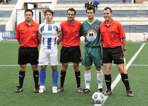 El trío arbitral con los capitanes del partido