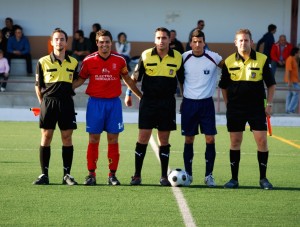 El trío arbitral con los capitnaes del partido