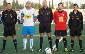 El trío arbitral con los capitanes del partido