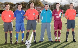 El trío arbitral con los capitanes del partido