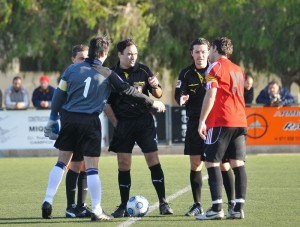 El trío arbitral con los capitanes del partido