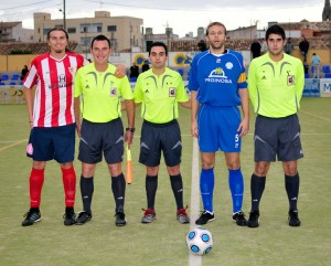 El trío arbitral con los capitanes del partido