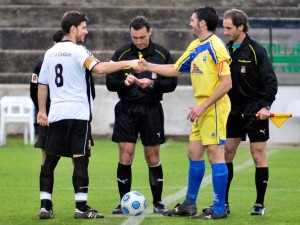 El trío arbitral con los capitanes del partido