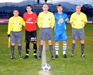 El trío arbitral con los capitanes del partido