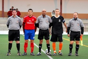 El trío arbitral con los capitanes del partido