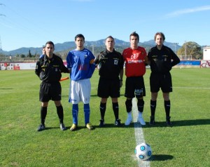 El trío arbitral con los capitanes del partido