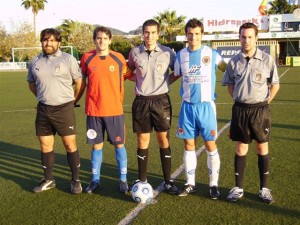 El trío arbitral con los capitanes del partido