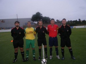 El trío arbitral con los capitanes del partido