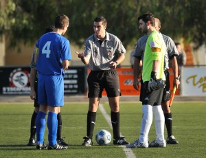 El trío arbitral con los capitanes del partido