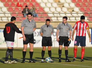 El trío arbitral con los capitanes del partido