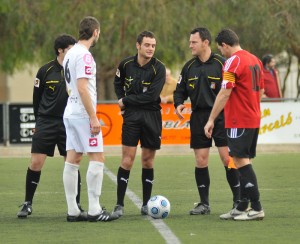 El trío arbitral con los capitanes del partido