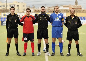 El trío arbitral con los capitanes del partido