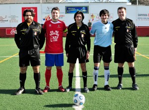 El trío arbitral con los capitanes del partido