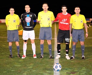 El trío arbitral con los capitanes del partido