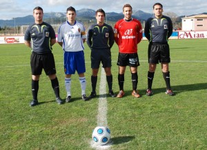 El trío arbitral con los capitanes del partido