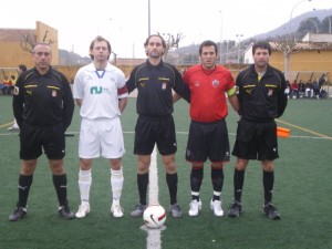 El trío arbitral con los capitanes del partido