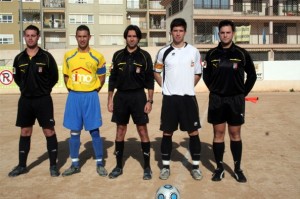 El trío arbitral con los capitanes del partido