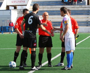 El trío arbitral con los capitanes del partido