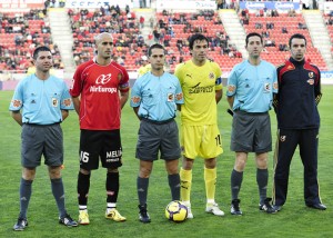 El trío arbitral con los capitanes del partido