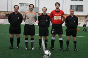 El trío arbitral con los capitanes del partido