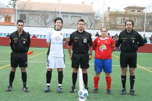 El trío arbitral con las capitanas del partido